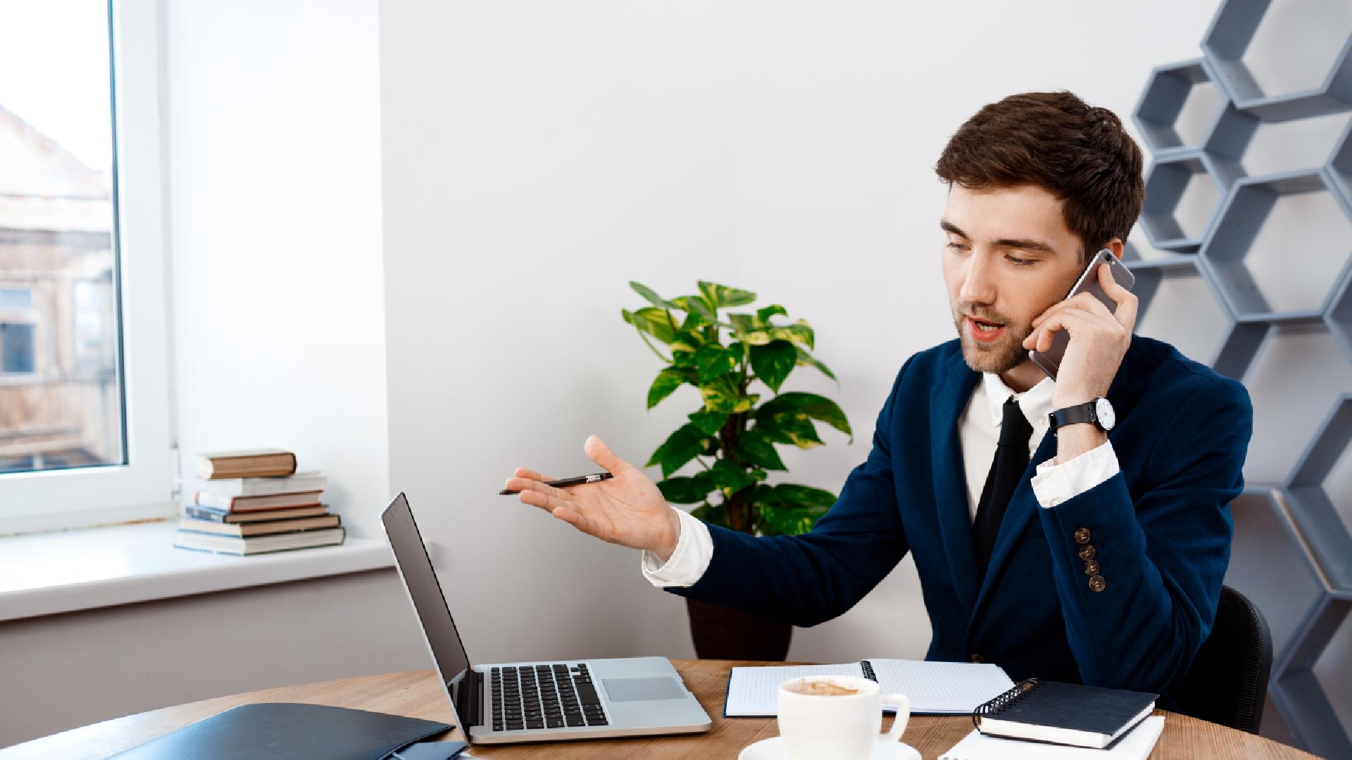 young-successful-businessman-speaking-phone-office-background